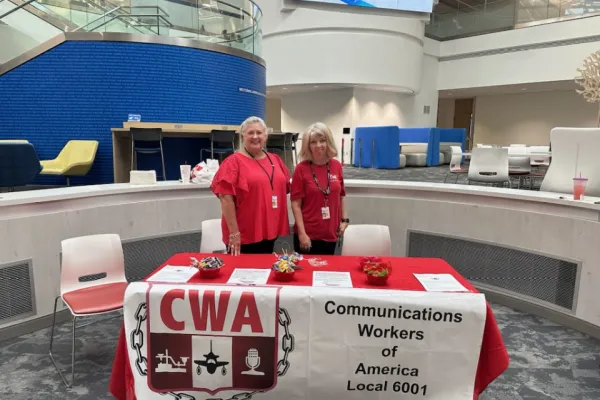 Two CWA members in red shirts stand behind a table with a CWA Local 6001 sign